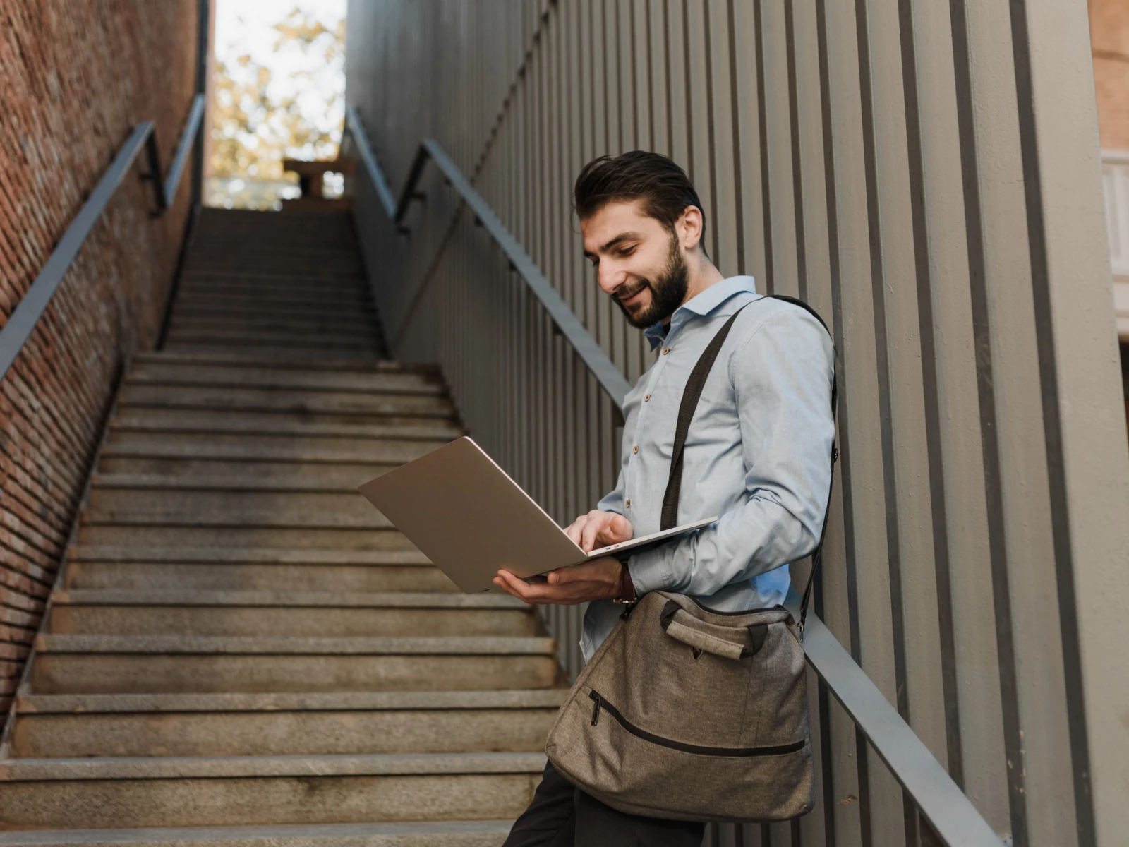 Confident businessman holding tablet walking through modern glass office corridor looking away thoughtfully