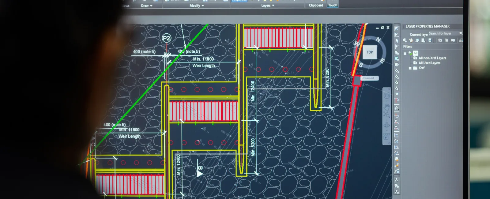 Person viewing detailed architectural or engineering diagram on computer screen with design software.