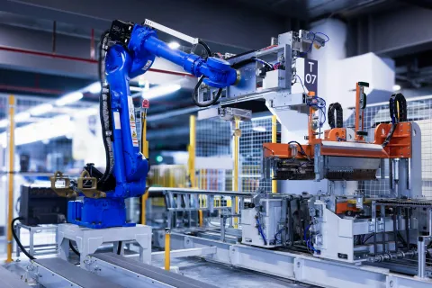 Blue industrial robotic arm operating machinery in a high-tech automated manufacturing factory